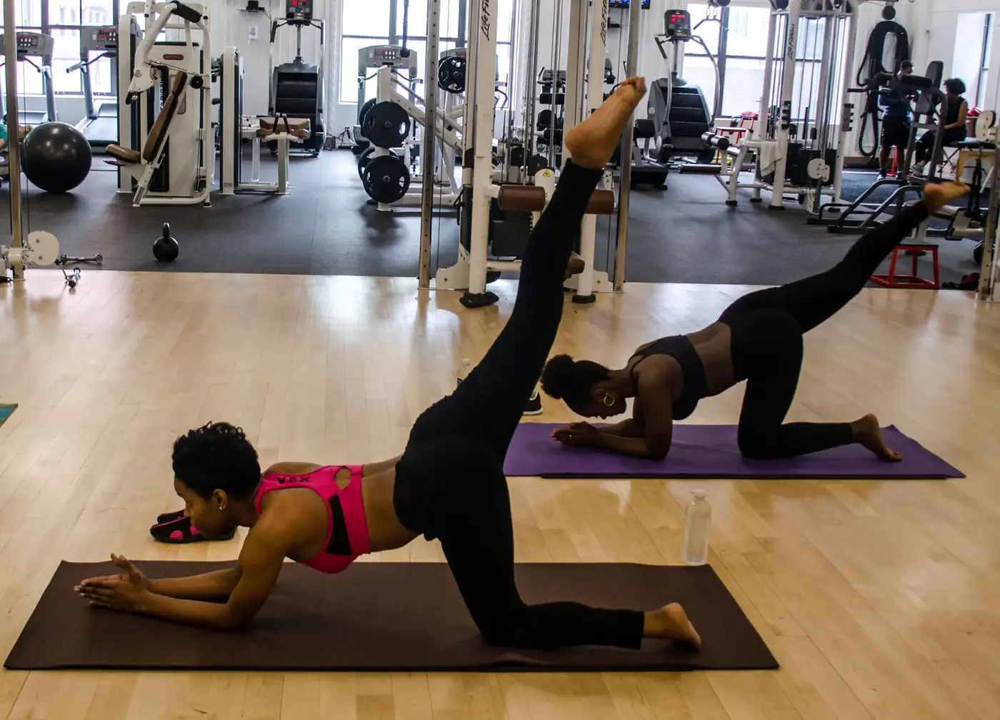Two students practicing a kneeling balance pose with one leg extended