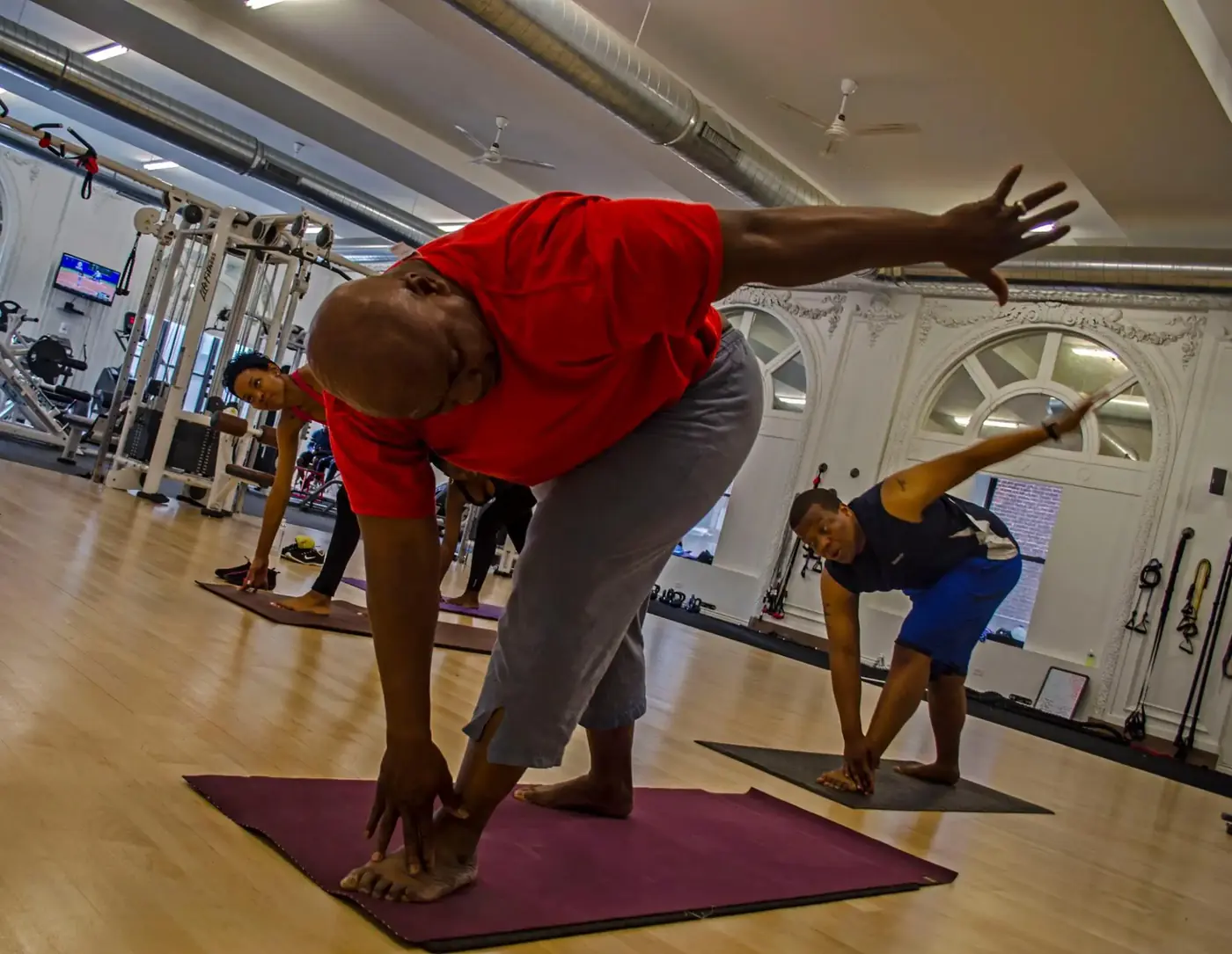 Akhu Yoga group class practicing a standing side stretch on their mats